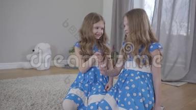 两个积极的白种人双胞胎姐妹穿着优雅的蓝色<strong>点缀</strong>连衣裙，握住对方的<strong>小</strong>手指，举起双手